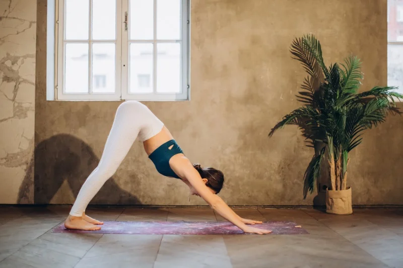 A person doing adho mukha asana with a straight back and arms extended, feeling both the benefits and potential drawbacks of the pose